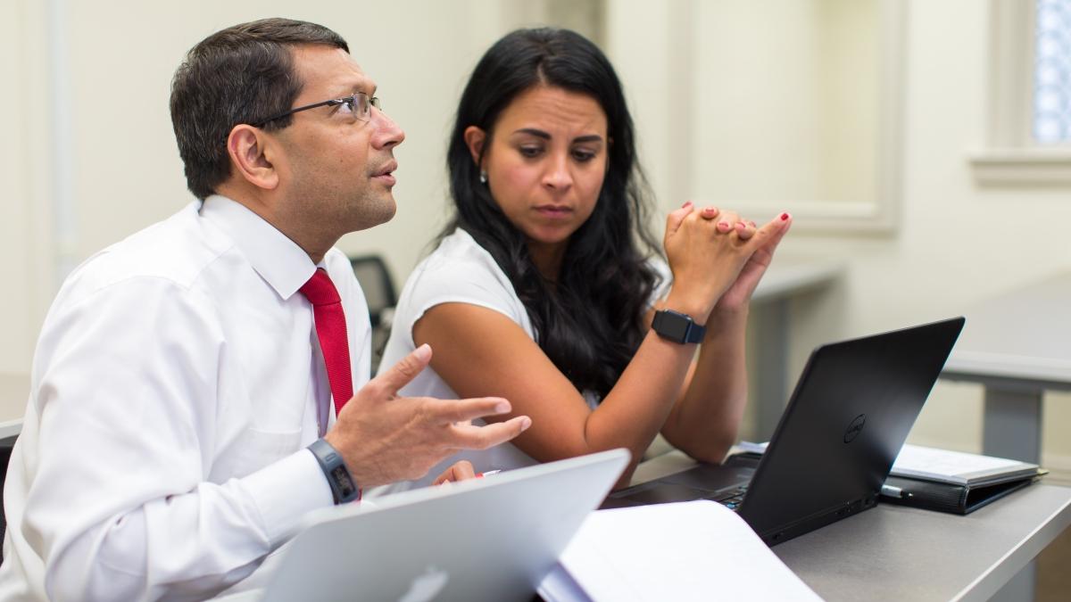 Two healthcare executives work together on laptops